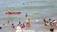 Pantai itu penuh sesak dengan orang ramai yang berenang pada tengah hari semasa Festival Perahu Naga.