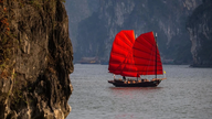 Seks røde trevæggede sejlbåde byder officielt turister velkommen i Ha Long-bugten.