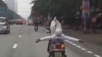 Người đàn ông buông tay “làm xiếc” với xe máy đang chạy trên phố