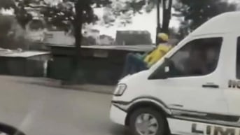 Người đàn ông ngồi trên nắp capo ô tô đang chạy trên Đại lộ Thăng Long