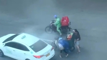 폭풍우에도 불구하고 한 남자가 판딘풍 거리에서 오토바이에서 떨어진 두 사람을 돕기 위해 달려나갔습니다.