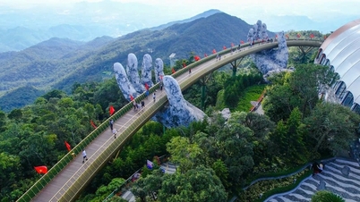 Los turistas toman fotografías con entusiasmo del Puente Dorado que brilla en rojo con la bandera nacional vietnamita el 2 de septiembre