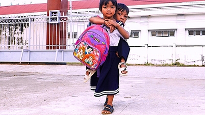 Cô bé lớp một cõng bạn đến lớp