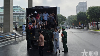 Hanoi: Officerare och soldater från Militärmedicinska akademin hjälper människor att ta sig över översvämmade områden.