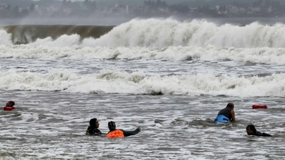 Muitas pessoas nadam no mar apesar das grandes ondas antes da tempestade Fengshen