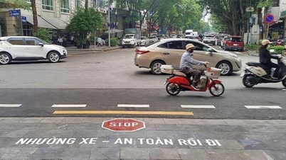 Polisi lalu lintas mengecat huruf-huruf di jalan untuk mengingatkan pengemudi agar berhenti ketika berpindah dari gang ke jalan utama.