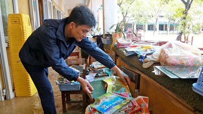 ספרים, שולחנות וכיסאות מכוסים בבוץ לאחר השיטפון, מורים ותלמידים בהואה עסוקים בניקיון בית הספר.