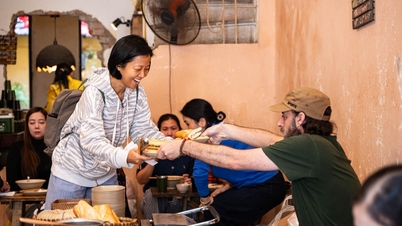 Western and Vietnamese guests line up and serve themselves vegetarian food in an old house in Hanoi.