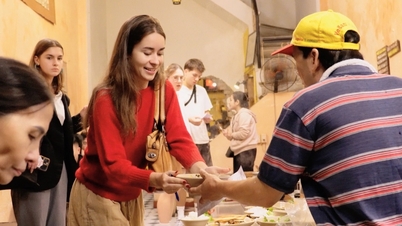 ភ្ញៀវទេសចរលោកខាងលិចអង្គុយ «នៅលើចិញ្ចើមផ្លូវក្នុងផ្ទះ» ដោយរីករាយនឹងអាហារបួសដែលបម្រើដោយខ្លួនឯងនៅក្នុងតំបន់ចាស់នៃទីក្រុងហាណូយ។