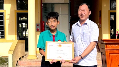Een mannelijke leerling uit de negende klas ontvangt een certificaat van verdienste voor het terugbrengen van een portemonnee met daarin bijna 23 miljoen VND.