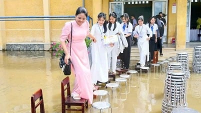 Les enseignants disposent des chaises pour faire un pont et conduisent les élèves à la cérémonie de remise des diplômes au milieu d'une cour d'école inondée
