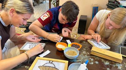 Turister njuter av upplevelsen av att mala ris och tillverka halmkvastar i Ninh Binh.