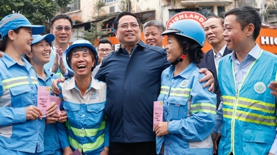 首相はお札を配り、路上で清掃作業員らと写真を撮った。