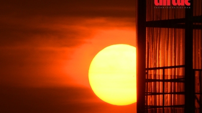 Matahari, seperti 'telur asin,' mewarnai langit di atas Kota Ho Chi Minh dengan warna oranye.
