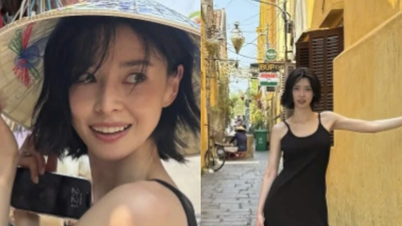 Koreansk skönhet bär en konisk hatt medan hon promenerar genom Hoi Ans antika stad.