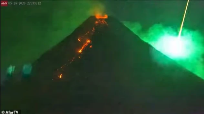 Seltenes Schauspiel: Ein blauer Meteor rast am Himmel vorbei an einem ausbrechenden Vulkan.