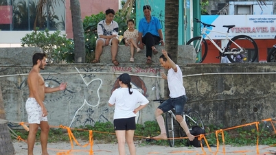 Ein Mann balanciert auf einem Seil am Strand von Da Nang, und Touristen versuchen es eifrig selbst.