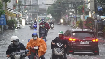 Människor kämpar för att skjuta sina motorcyklar efter kraftigt regn i Ho Chi Minh-staden.