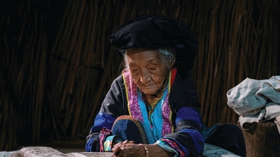A 97-year-old artist skillfully paints with beeswax on the rocky plateau.